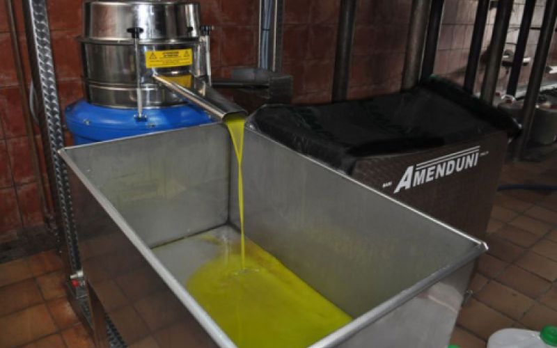 Máquina depositando aceite en cubeta metálica